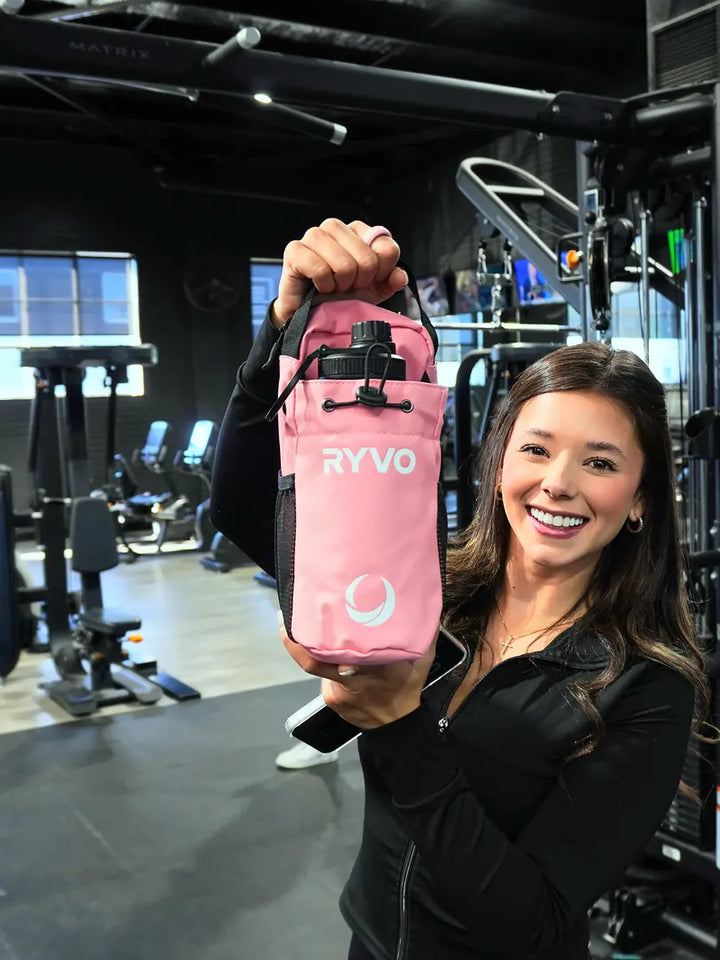 Smiling woman in the gym holding up the pink RYVO Rig magnetic gym bag