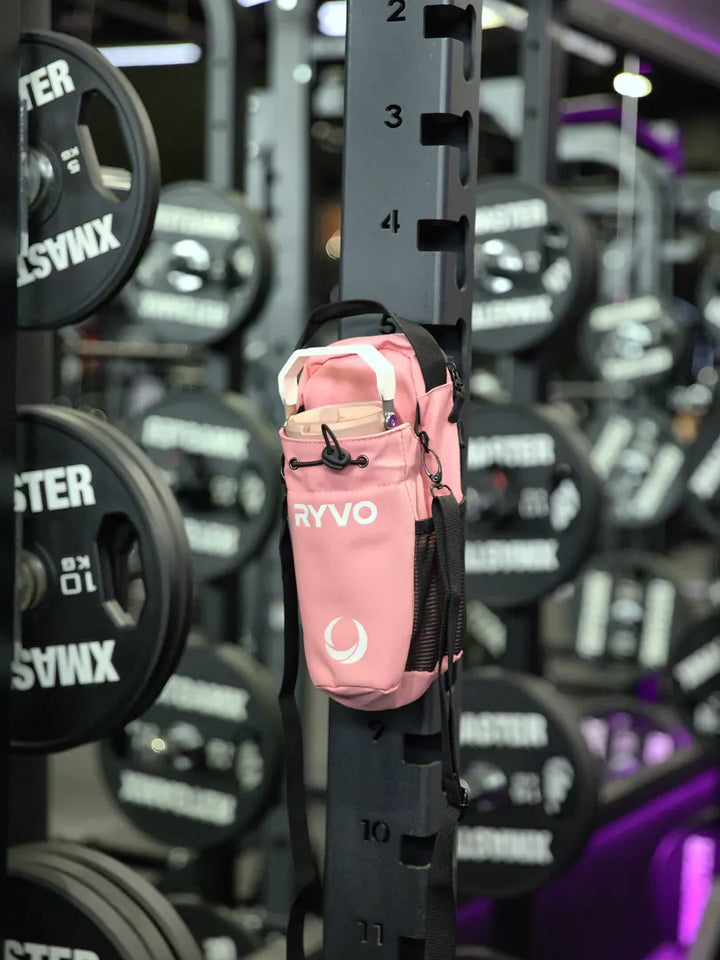 Pink RYVO Rig magnetic gym bag attached to a weight plate rack