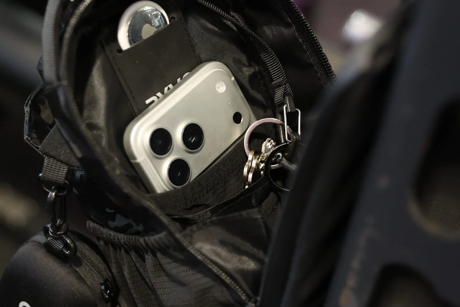 Looking into an open black camo RYVO magnetic gym bag, with a phone, keys on a clip and a RYVO earbud case packed into its inner pockets, ready for a gym session.