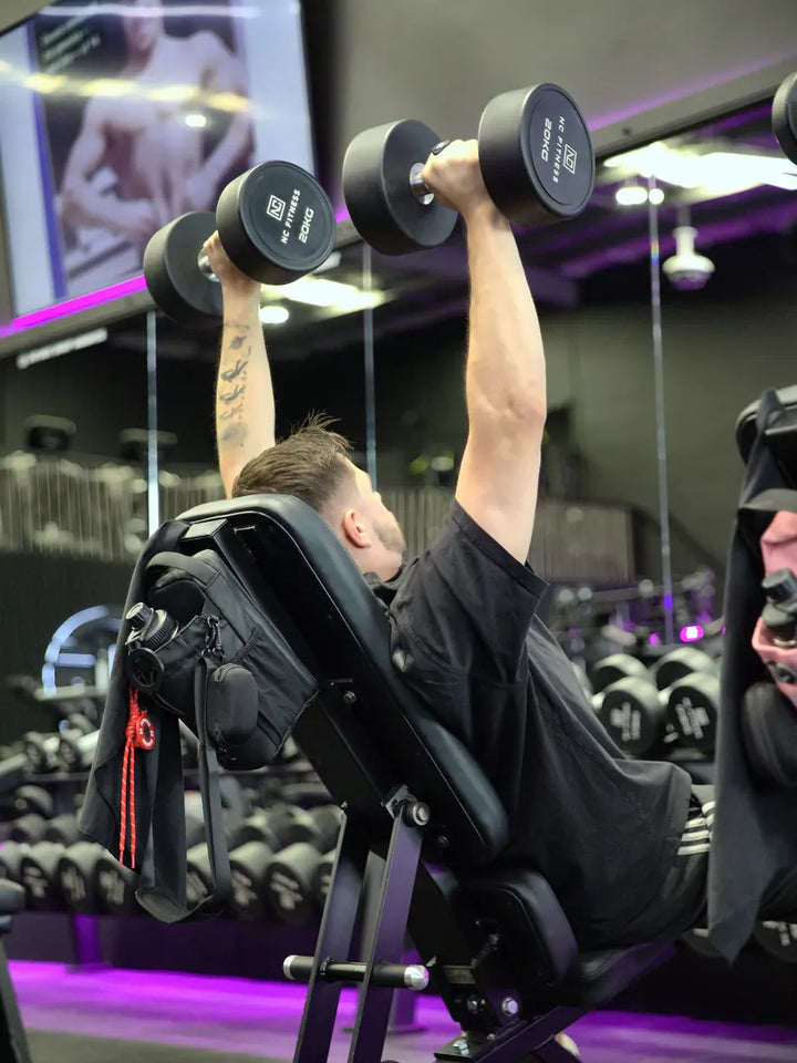 Man doing a dumbbell press with the black RYVO Rig Pro on the bench beside him